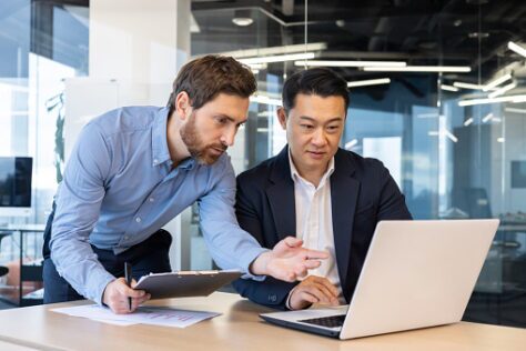 Two men conferring about PDF accessibility while looking at a laptop in the enterprise sector.