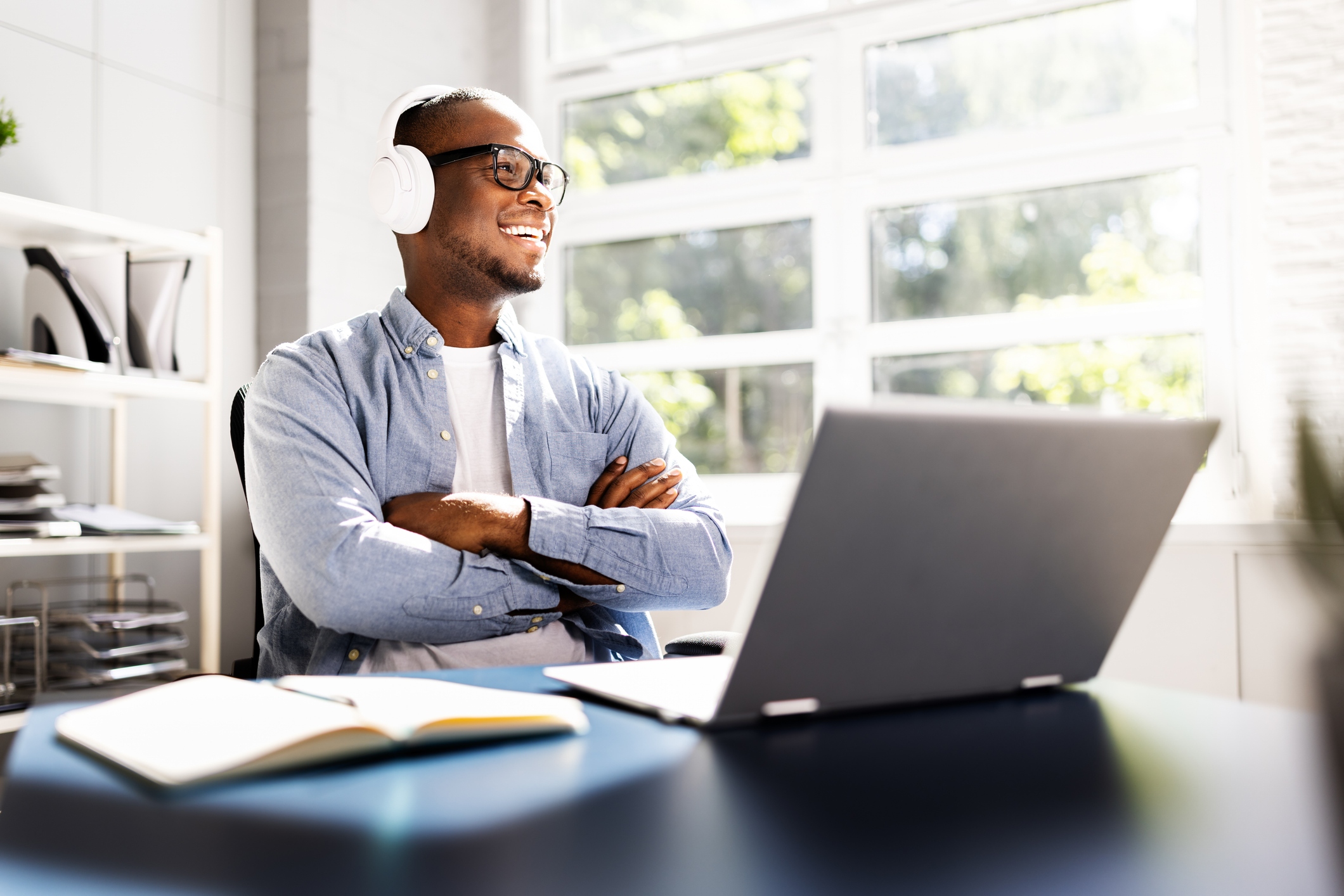 Man working on a laptop wearing headphones and smiling, enjoying his customer experience.