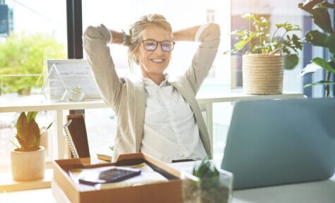 Business woman feeling accomplished and enjoying a break to stretch with hands behind her head in an office. Happy mature entrepreneur satisfied and relieved to have completed her deadlines and tasks