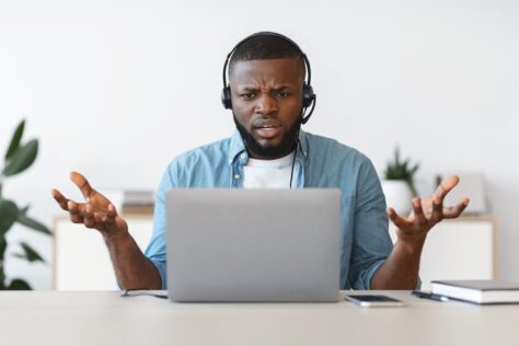 Annoyed student with headphones and laptop