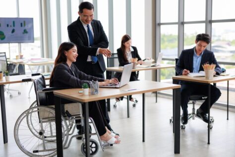 Coworkers in suits discussing digital accessibility law in an office.