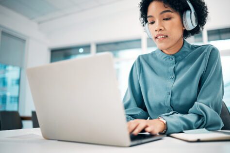 A woman using a laptop to read a PDF and happy she doesn't have an alternative format