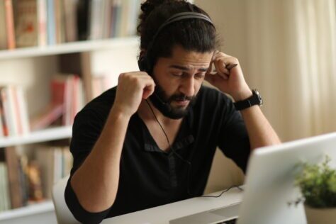 Frustrated man in headphones trying to read PDF document, dealing with poorly tagged PDFs.