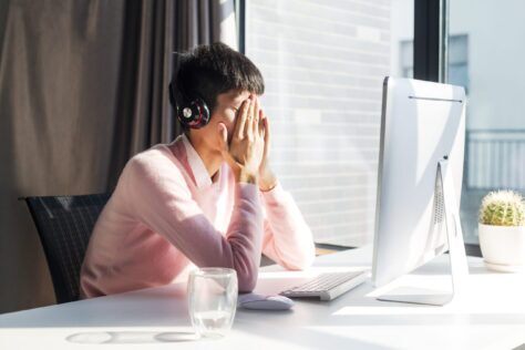 Blind person wearing headphones upset at their laptop