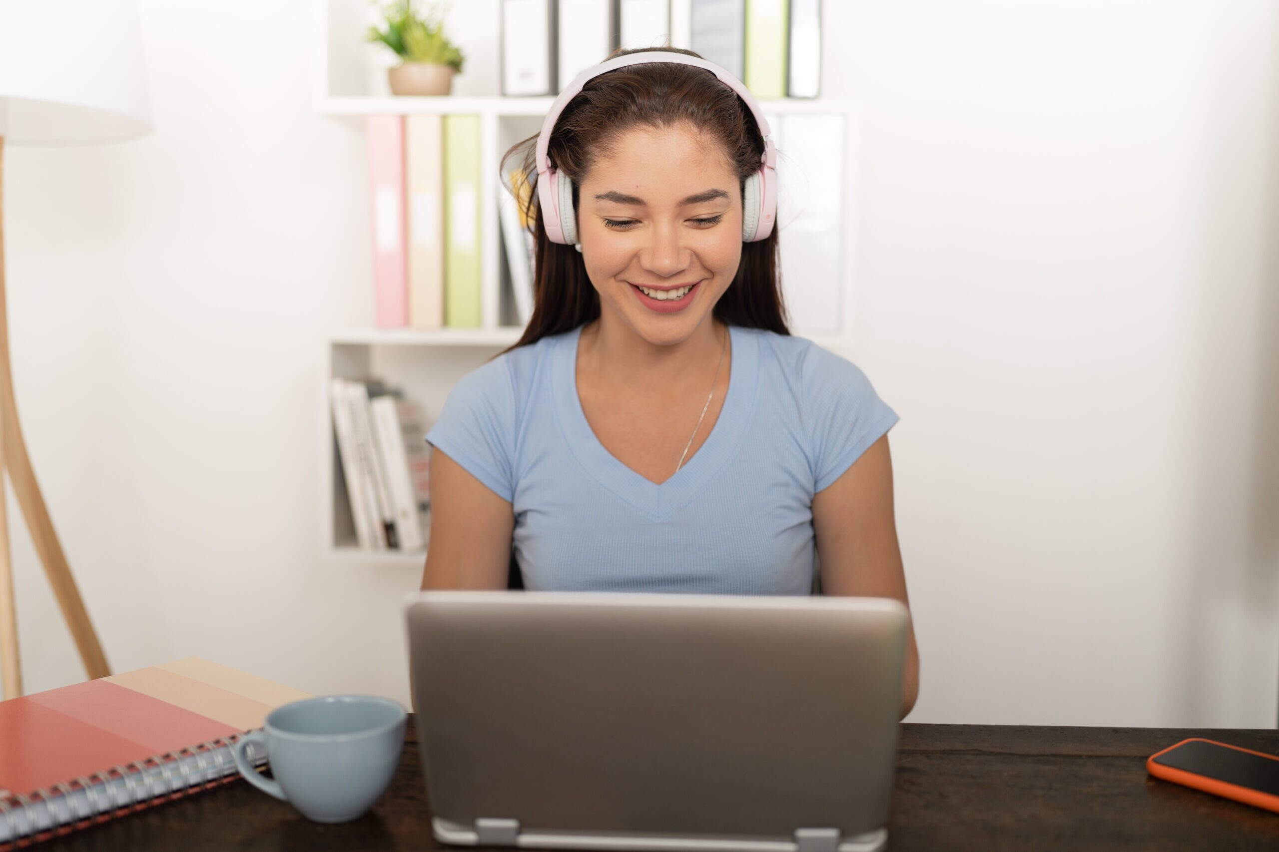 Woman working at a laptop with headphones on, using a PDF accessibility checker.