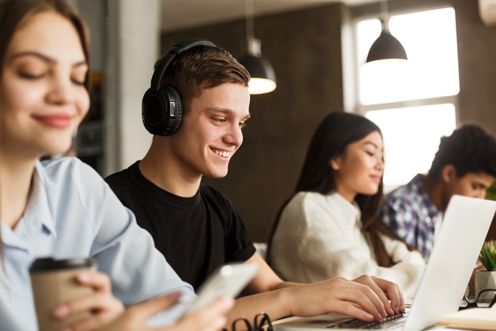 Students working on laptops. One of them is wearing headphones, please as his accessible academic content.