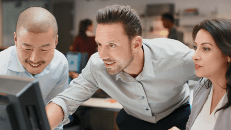 Team evaluating Equidox AI at a computer. Everyone looks pleased and excited.