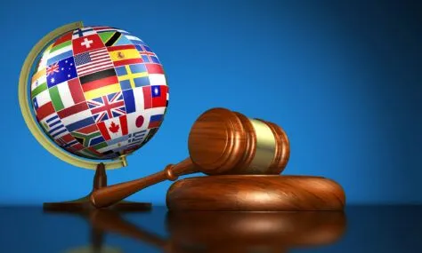 Gavel and globe with international flags indicating penalties of inaccessible PDFs.