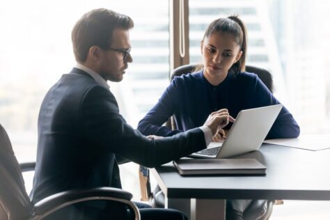 Two people conferring over a laptop about the ROI of automated PDF remediation