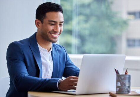 Smiling man remediating PDFs on a laptop working on Section 508 and ADA compliance.